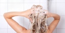person washing their hair in shower with shampoo