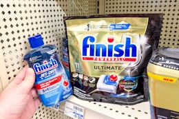 hand holding finish jet dry next to shelf with dishwasher tabs