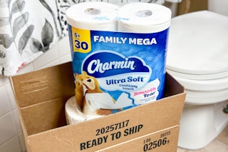 some charmin toilet paper packages in a box sitting in front of a toilet