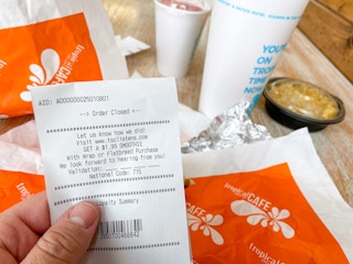 A person holding a Tropical Cafe smoothie receipt.