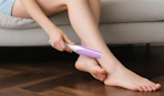 a person holding a purple and white glass foot file near their feet