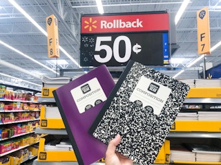 hand holding two composition notebooks in front of $0.50 sale sign