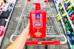 person holding a large bottle of old spice body wash over a cvs cart
