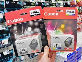 a person holding canon printer ink in a store