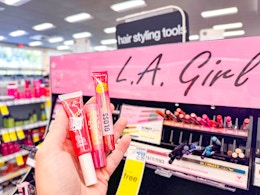 hand holding lip products in front of l.a. girl display in cvs