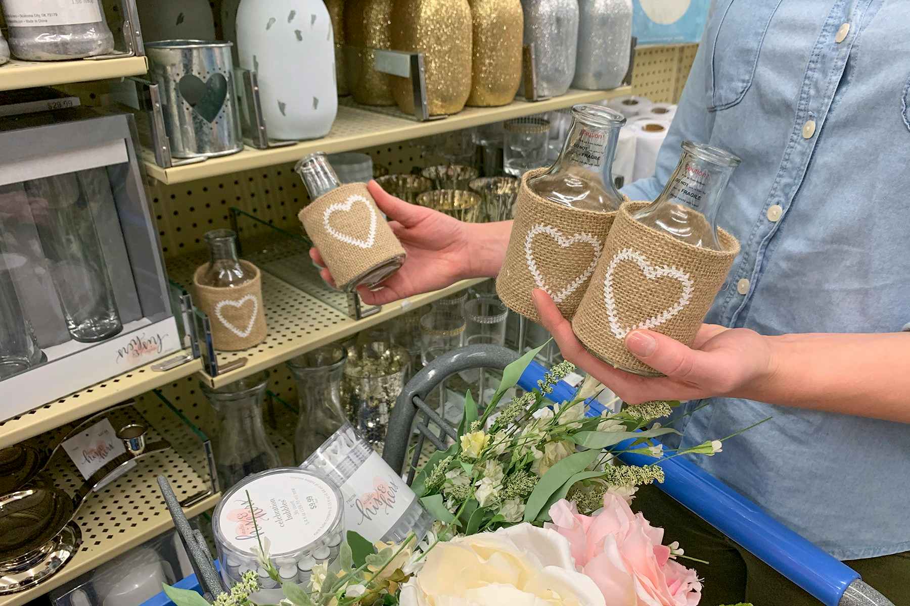 A woman holding multiple vases, wrapped in burlap with a heart shape stamped on the front of them.