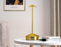 a gold cordless lamp on a table 