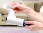a hand pulling paper off of a lint roller