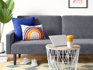A Room Essentials Futon Sofa with Arms with some throw pillows in a living room.