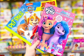 hand holding Pet Pals, Paw Patrol, and My Little Pony jumbo coloring books