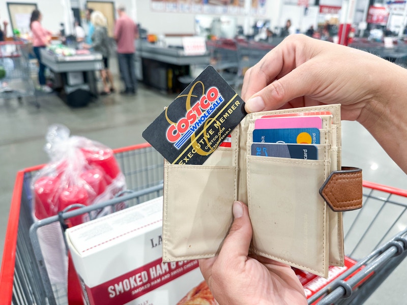 a person holding up a costco card out of wallet at checkout