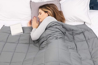 person sleeping on a bed with a grey weighted blanket