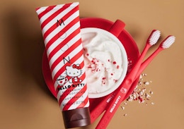 a tube of Hello Kitty toothpaste next to red toothbrushes