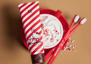 a tube of Hello Kitty toothpaste next to red toothbrushes