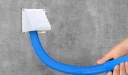 a hand holding a hose while cleaning a dryer vent