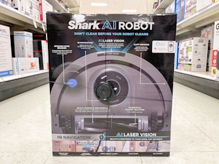 A Shark AI Robot sitting in the middle of a store aisle on the floor.