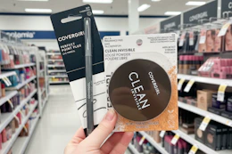 person holding covergirl eyeliner and setting powder in an aisle