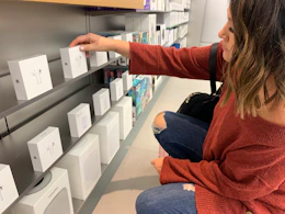 a person picking up a box of Apple Airpods in a store