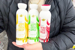 person holding three bottles of Dove plant milk body wash