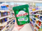 person holding a tub of cascade pods in an aisle
