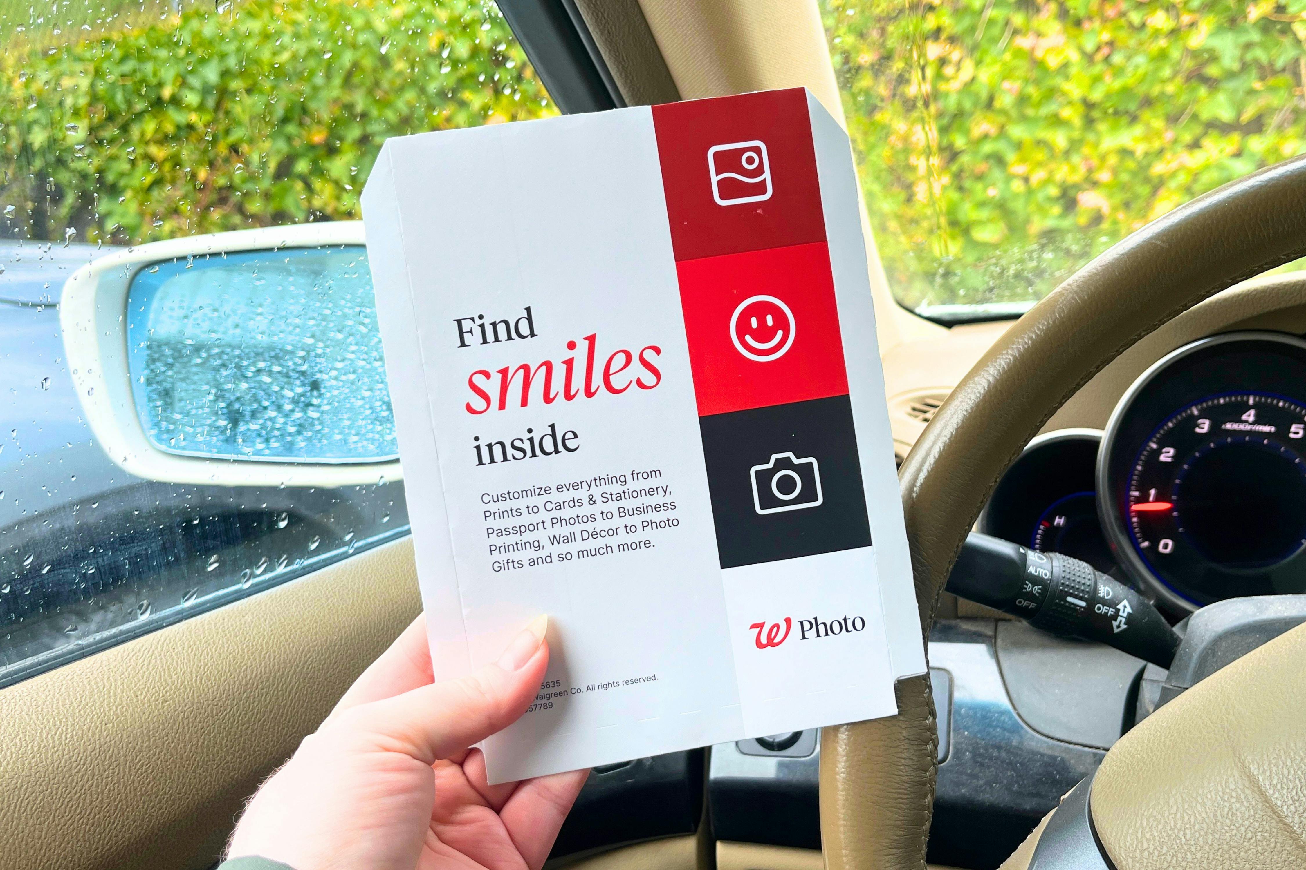 hand holding a walgreens photo packet in a car