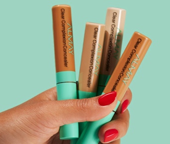 a hand holding tubes of concealer 
