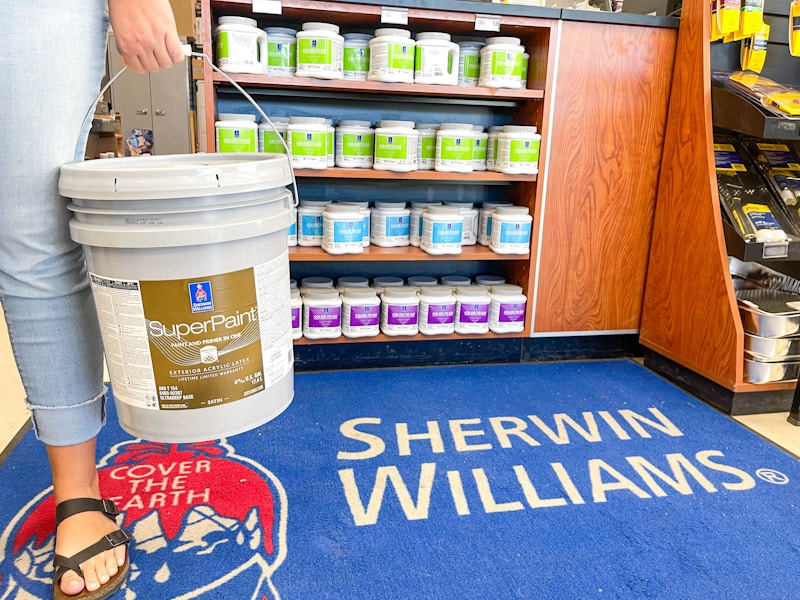 woman holding up a 5 gallon paint bucket in sherwin williams store 