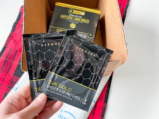 hand holding two packs of eye patches over packaging