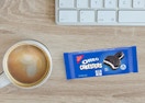 a Oreo Cakester packs on a desk next to a cup of coffee