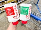 Bottles of Chick-fil-A barbeque and sweet & spicy sriracha sauce held in front of a Walmart cart