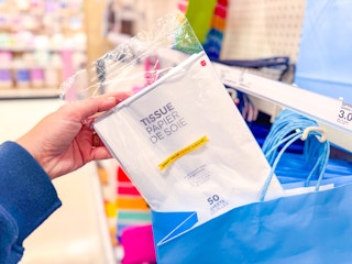hand holding a pack of american greetings tissue paper in gift bag at target
