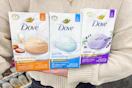 person holding three packs of Dove beauty bars