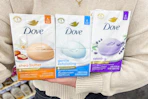 person holding three packs of Dove beauty bars