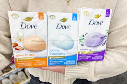 person holding three packs of Dove beauty bars