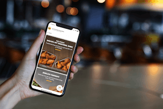 A person holding their iPhone up showing the Buffalo Wild Wings app open to the promotional page.