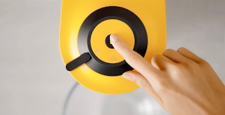 hand pushing button on nespresso machine to begin cleaning