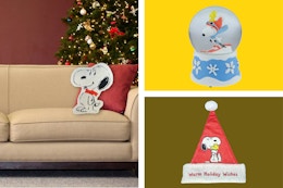 peanuts snowglobe, santa hat, and pillow sitting side by side