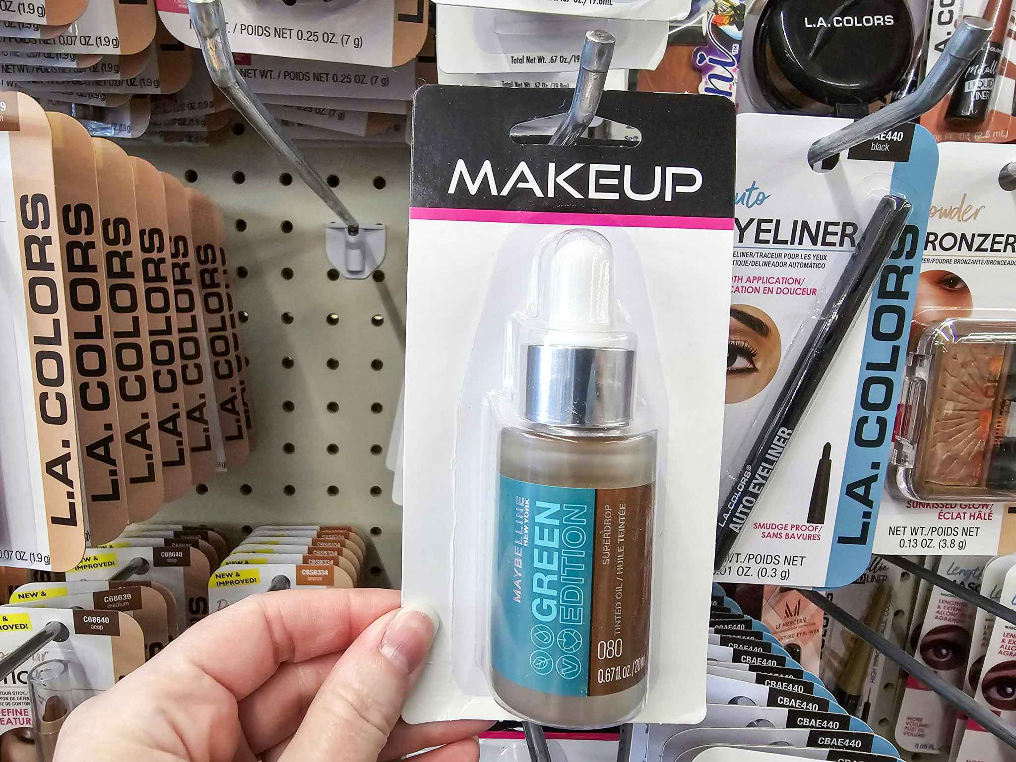 person grabbing a maybelline foundation off a hook at dollar tree