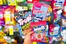 person holding bags of trolli, nerds, and sweettarts candy