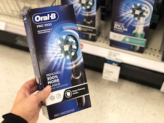 a hand holding an electric toothbrush box in an store aisle