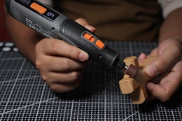 person using rotary tool on piece of wood
