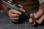 person using rotary tool on piece of wood