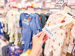 hand grabbing a carter's baby sleep & play off a target shelf