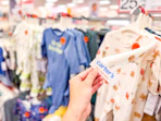 hand grabbing a carter's baby sleep & play off a target shelf