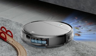 a silver robot vacuum on a rug near a couch