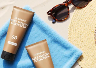 brown tube of sunscreen on a towel on a beach