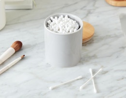 cotton swabs in a small jar on a marble counter