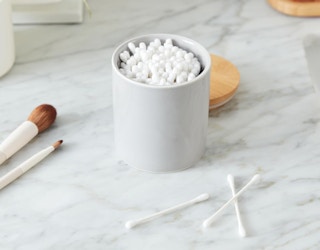 cotton swabs in a small jar on a marble counter