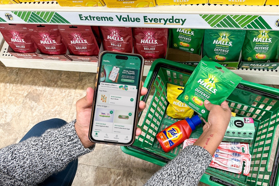 a person holding an iphone with a coupon app in the dollar tree store