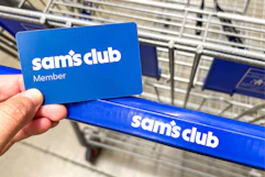 hand holding a sams club membership card over shopping cart